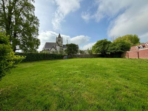 a large field of grass with a building in the background at Gîte des 6 tilleuls in Bomy