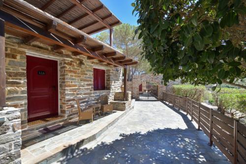 a brick house with a red door and a wooden fence at KEOS by the sea in Korissia