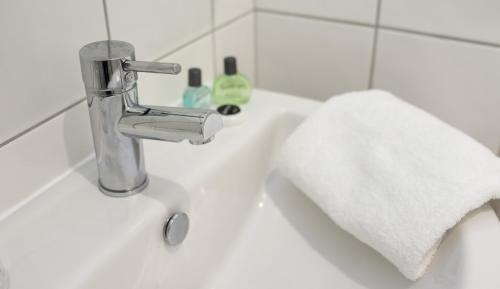 a bathroom sink with a faucet and a towel at Warren Lodge in Shepperton
