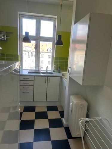 a kitchen with a sink and a window and a checkered floor at Cozy Corner in Aalborg