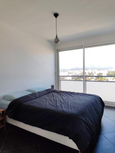 un lit dans une chambre avec une grande fenêtre dans l'établissement Appart vu panoramique Marseille, à Marseille