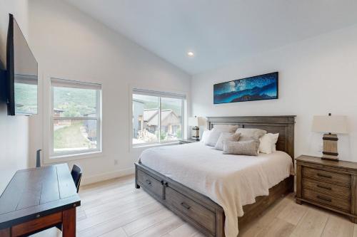 a bedroom with a bed and a desk and windows at Sunlight cottage in Steamboat Springs