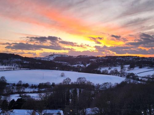 a sunset over a snow covered field with the sky at Luxury 1 Bed Coach House in Huddersfield