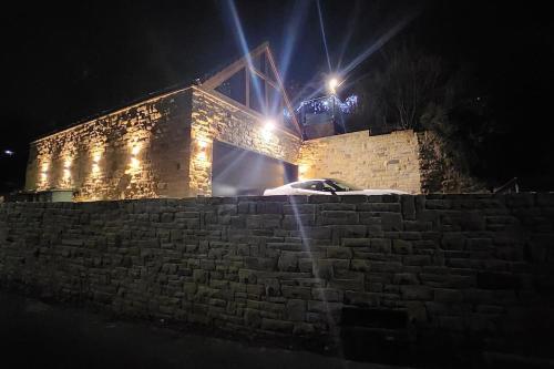a brick building with a car parked on a wall at night at Luxury 1 Bed Coach House in Huddersfield