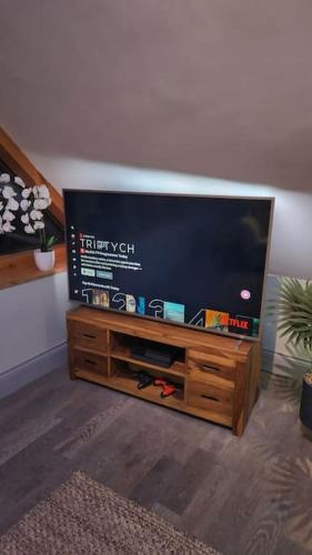a flat screen tv sitting on a wooden entertainment center at Luxury 1 Bed Coach House in Huddersfield