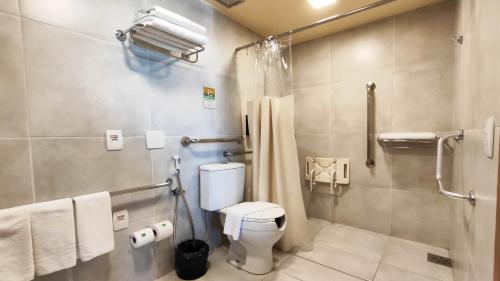 a bathroom with a toilet and a shower with towels at Holiday Inn Fortaleza by IHG in Fortaleza