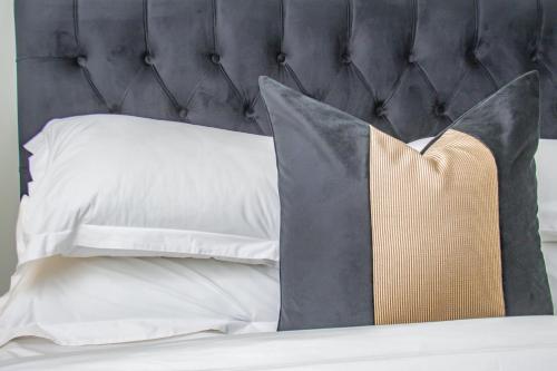 - un lit avec des oreillers blancs et une tête de lit noire dans l'établissement Exclusive Apartment, Ellipse, à Midrand