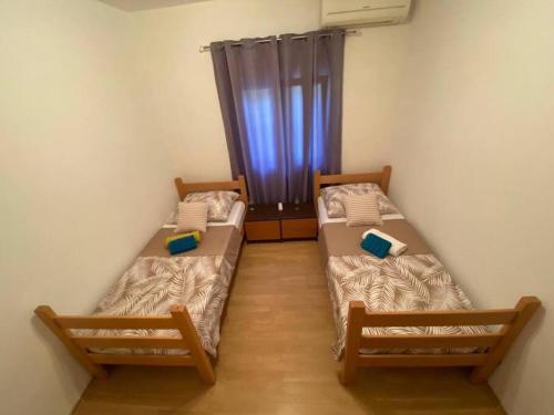 two beds in a small room with a window at Apartment Maribel in Tribanj-Krušćica
