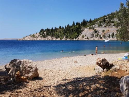 a beach with rocks and people in the water at Apartment Maribel in Tribanj-Krušćica