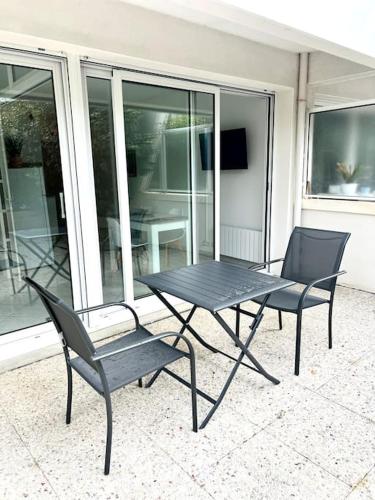 une table noire et deux chaises sur une terrasse dans l'établissement Porte Océane studio spacieux avec parking, à La Rochelle