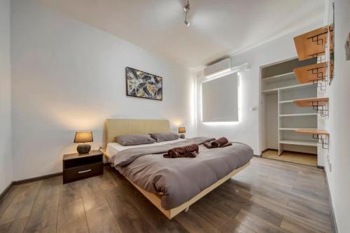 a bedroom with a large bed and wooden floors at Modern Penthouse Near Gzira Seafront in Il-Gżira