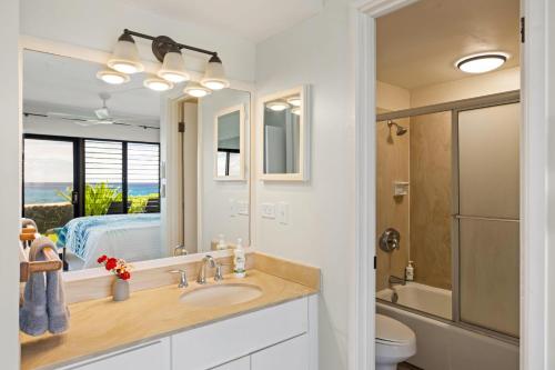 ein Badezimmer mit Waschbecken und Spiegel und einem Bett in der Unterkunft Poipu Shores 107A in Koloa