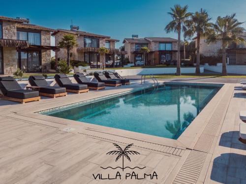 a swimming pool with lounge chairs in front of a building at Villa Palma in Kallithea Halkidikis