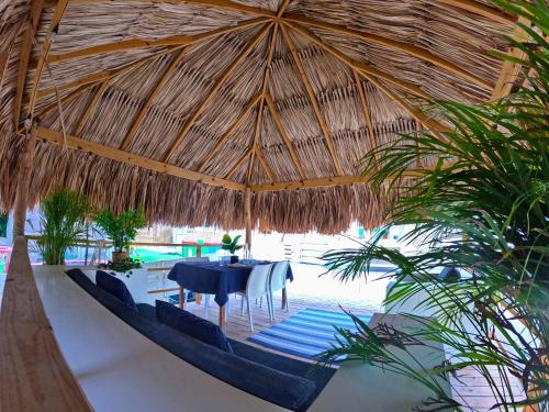 a dining room with a table under a straw umbrella at 4BlessingsCuracao1 in Willemstad