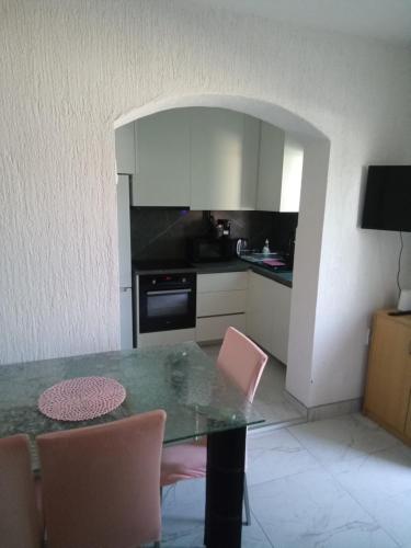 a kitchen with a table with pink chairs and a counter at Apartman Pavic in Pag