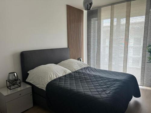 a bedroom with a bed with a blue blanket and a window at STAR Apartament & Spa Dziwnów in Dziwnów