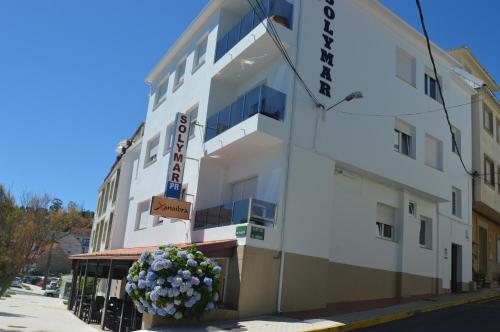a white building with flowers in front of it at Hostal Solymar in Louro