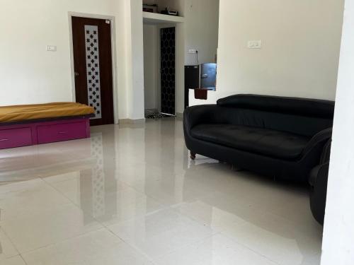 a living room with a black couch and a tv at Emerald Village in Kālapettai