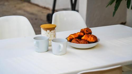 a white table with a bowl of food and two cups at New - Parking - Wifi - Jardin - Le Refuge D'Abel in Avignon