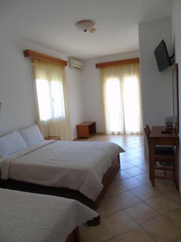 a bedroom with a bed and a desk and windows at Studios - Nostos in Chrysi Ammoudia