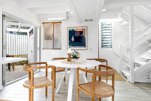 a dining room with a white table and chairs at 2-Bed Coastal Haven with Pool by Sunshine Beach in Sunshine Beach