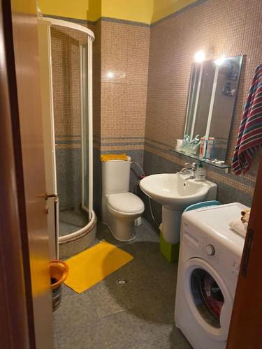 un bagno con WC, lavandino e lavatrice di Sunset Serenity Apartment a Durrës