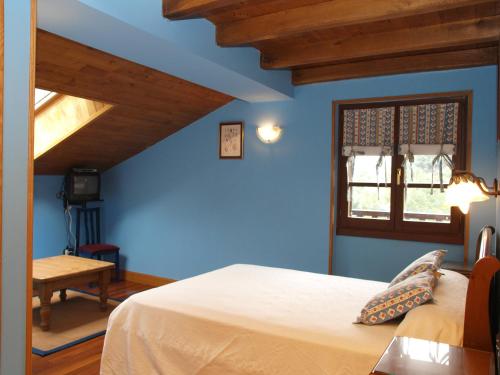 a blue bedroom with a bed and a window at Hostal Rural Onbordi in Lesaka