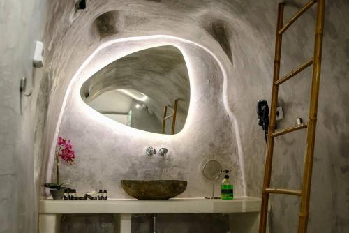 a bathroom with a sink and a large mirror at EvnOikon II Amazing Jacuzzi-Cave House in Fira in Fira