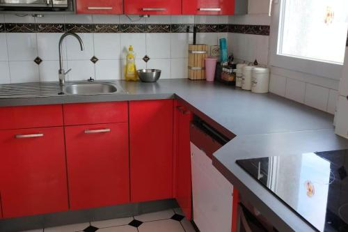 a kitchen with red cabinets and a sink at Appartement terrasse et jacuzzi in Aulnay-sous-Bois