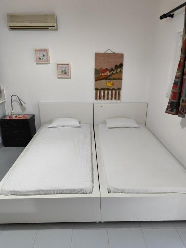 two beds in a room with white walls at CottonClub Villas in Tolo