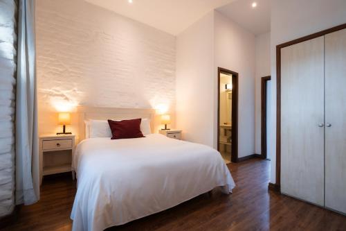 a bedroom with a white bed with a red pillow at Don Antonio Posada in Colonia del Sacramento