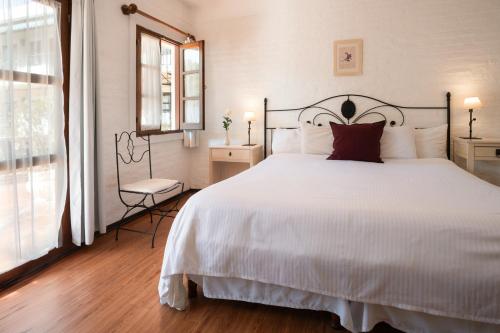 a bedroom with a large white bed and a window at Don Antonio Posada in Colonia del Sacramento