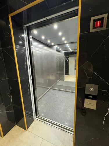 a glass shower door in a bathroom with a mirror at Moonlight Apart-Hotel Batumi in Batumi