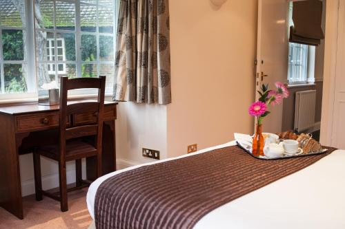 a hotel room with a bed and a desk and a table at Warren Lodge in Shepperton