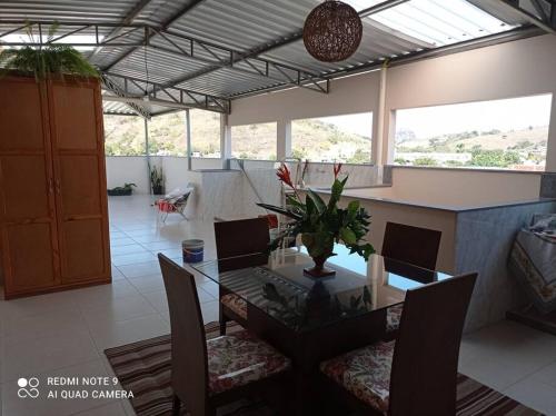 uma sala de jantar com mesa e cadeiras de vidro em Cobertura em Aperibé em Aperibé