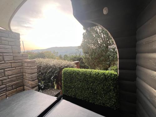 a view from the outside of a house with a hedge at LARCHES LODGE Norwegian log cabin, wood stove & spa in Church Stretton