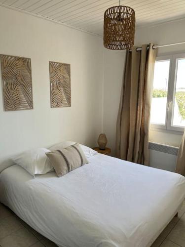 - un lit blanc dans une chambre avec fenêtre dans l'établissement Charmante Maison de Plage, à Bretignolles-sur-Mer
