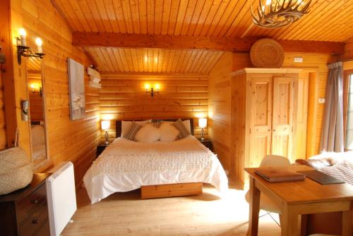 a bedroom with a bed in a wooden cabin at LARCHES LODGE Norwegian log cabin, wood stove & spa in Church Stretton