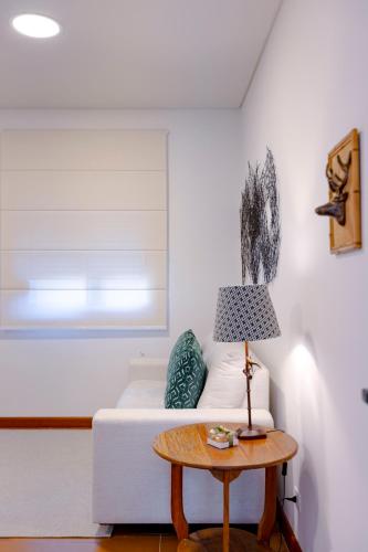 a living room with a white couch and a table at Zur Suítes in Campos do Jordão