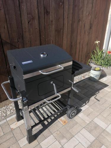 a barbecue grill on a cart in front of a fence at Bergwitzer Traumhaus in Kemberg