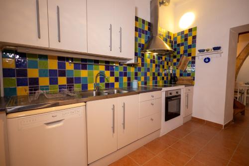 a kitchen with white cabinets and colorful tiles on the wall at Villa Irini in Kallithea Rhodes