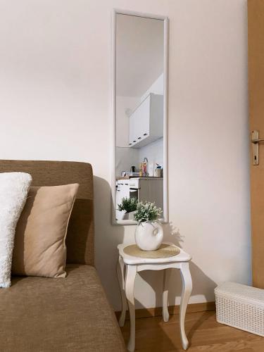 a mirror on a wall next to a couch with a table at Unik's Studio Apartment in Prizren