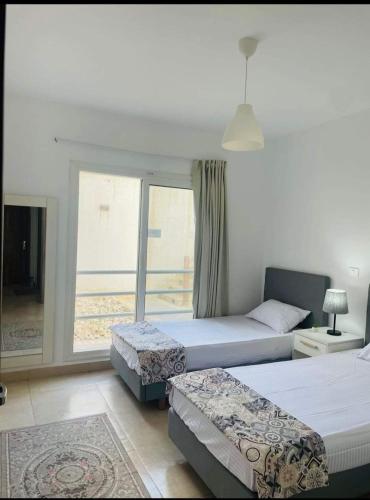 a hotel room with two beds and a window at أمواج الساحل الشمالي in Sīdī ‘Abd ar Raḩmān