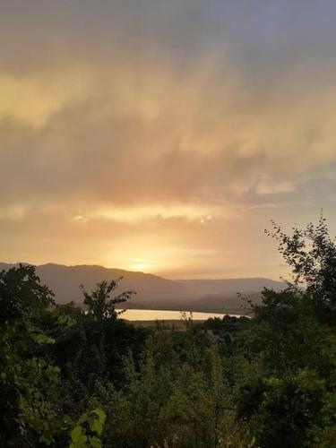 a sunset over a body of water with trees at Sara & Mateo Guesthouse in Libohovë