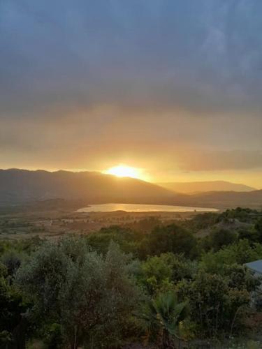 a sunset over a body of water with the sun setting at Sara & Mateo Guesthouse in Libohovë