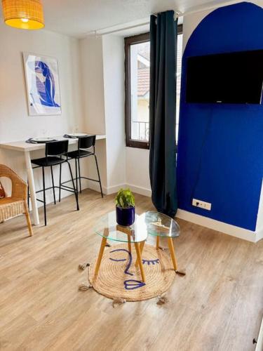 un salon avec une table et un mur bleu dans l'établissement Studio MILOS cosy hypercentre historique Thonon, à Thonon-les-Bains