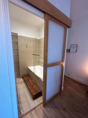 La salle de bains est pourvue d'une baignoire et d'une porte en verre. dans l'établissement 3 pièces dans le coeur du 16e, à Paris