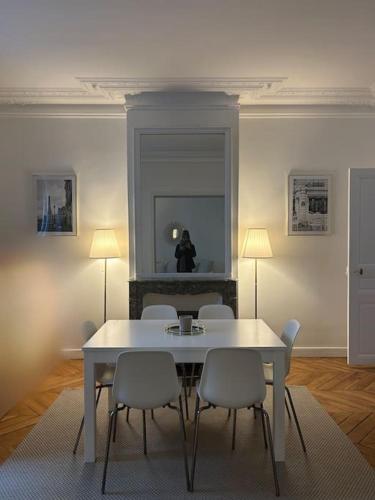 une salle à manger avec une table et des chaises blanches dans l'établissement 3 pièces dans le coeur du 16e, à Paris
