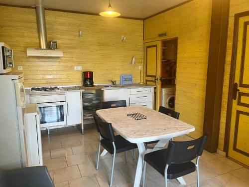 une cuisine avec une table et des chaises ainsi qu'une cuisine avec une cuisinière dans l'établissement La cabane du pêcheur - 20 min d'Aurillac - 2ch - les pieds dans le lac, à Lacapelle-Viescamp