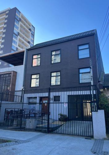 a black building with a fence in front of it at Hostal Ayiwün in Concepción